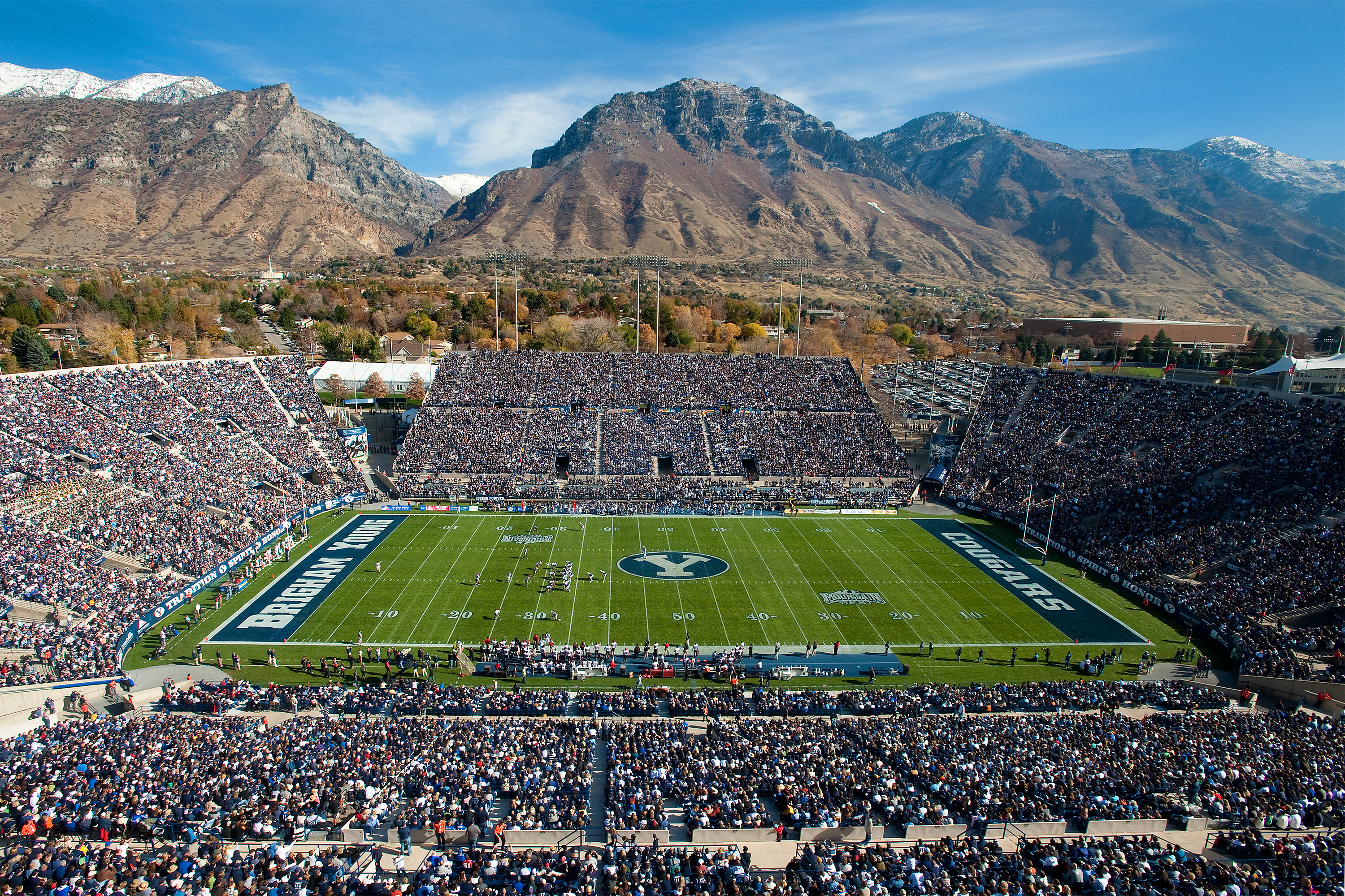 Packed college football stadium with mountain backdrop